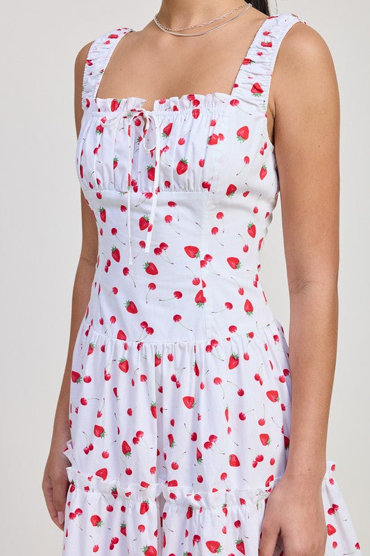 White dress with red strawberry pattern worn by a person on a plain background