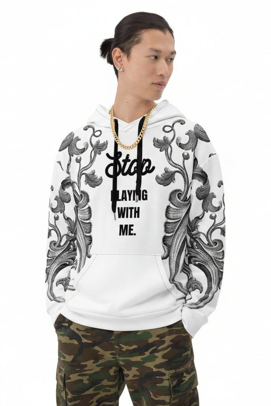 A person wearing a white unisex hoodie with a text and floral pattern on the sleeves, standing in front of an orange backdrop.
